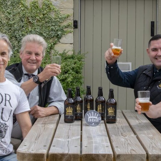 Lord Bathurst and the owners of Corinium Ales brewery sitting round a picnic table at the old kennels enjoying a drink of BBB beer